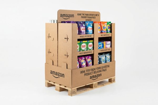 Brown corrugated cardboard Amazon half pallet display on a wooden pallet, stocked with Crisp, Tide, Fairy, Zippo, Lenor, and Bold laundry pods, featuring