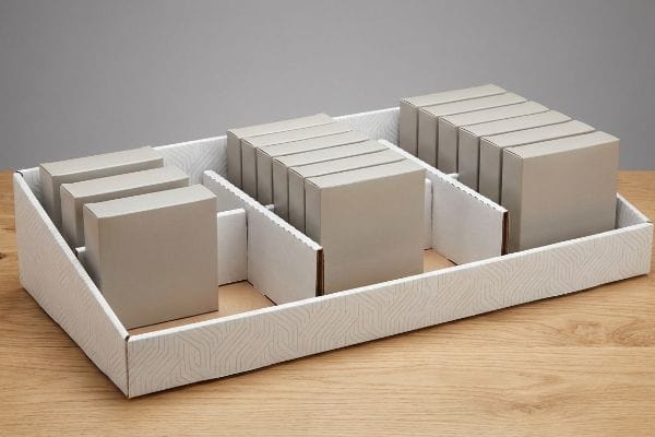 Plateau en carton blanc avec séparateurs modulaires présentant des groupes de références marron clair pour une présentation asymétrique des marchandises.