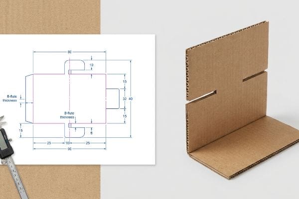 Brown corrugated B-flute cardboard display stand dieline with bend allowance dimensions and a physical folded sample showing interlocking slots.
