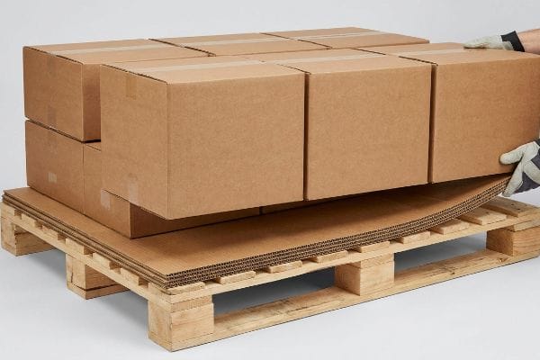 Lámina deslizante de cartón corrugado de doble pared que sirve de soporte a las cajas maestras marrones sobre un palé de madera, evitando que se hundan en los huecos de la plataforma.