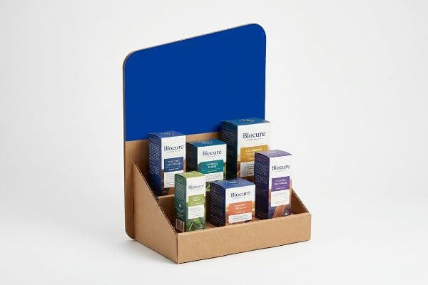 Présentoir PLV en carton ondulé présentant six boîtes de produits Biocure, notamment les variantes Soutien immunitaire, Boost d'énergie et Aide au sommeil.