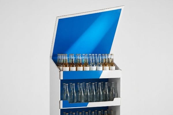 White and blue cardboard retail display with labeled beverage bottles on the top shelf and empty glass bottles below, designed for optimal product visibility.