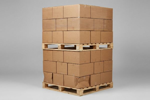 Brown cardboard boxes stacked on wooden pallets, showing bottom tier compression failure and buckling from overhang.