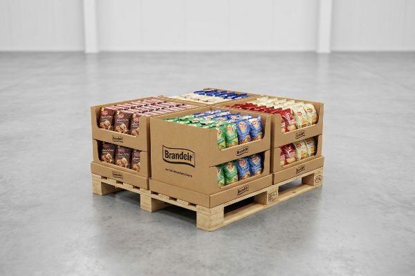 Wooden quarter-pallet supporting a brown cardboard Brandeli display with tiered snack bags in green, blue, red, and beige.
