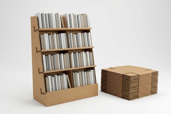 Assembled corrugated cardboard book display stand with books, alongside flat-packed retail merchandising components.
