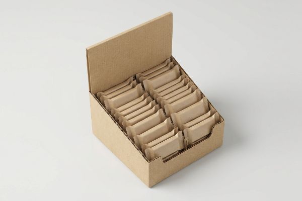 A brown corrugated cardboard counter display box filled with individually wrapped products, showcasing retail packaging.