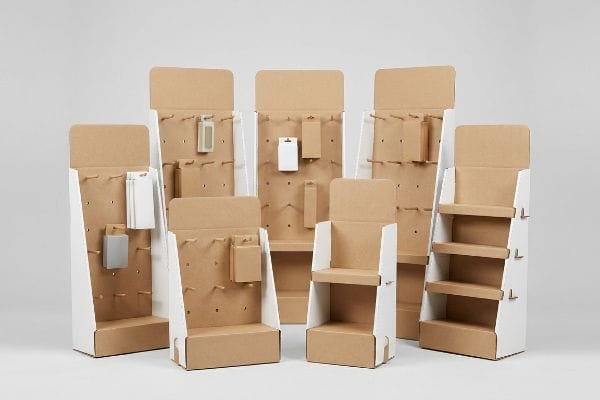 Various natural kraft cardboard retail hanging displays and shelf merchandisers with peg hooks, some holding small generic items.