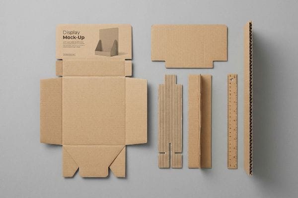 Flat-packed cardboard Display Mock-Up components for a retail stand, including die-cut pieces and a ruler, arranged on a gray surface.