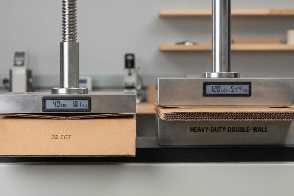 Two cardboard boxes under crush test, 32 Ect holding 40 Lbs (18.1 Kg) and Heavy-Duty Double-Wall holding 120 Lbs (54.4 Kg).