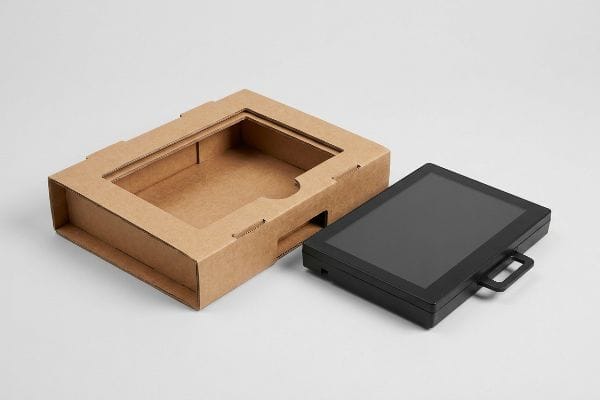 Brown corrugated cardboard display box with a die-cut friction-lock cavity next to a black flat screen monitor for e-waste separation.