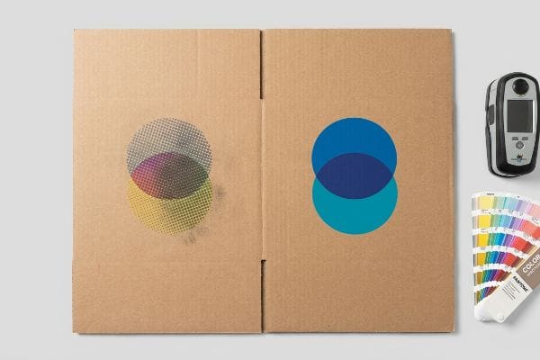 Des panneaux en carton présentent des points de trame CMJN et des couleurs Pantone unies, ainsi qu'un spectrophotomètre et des échantillons de couleurs.