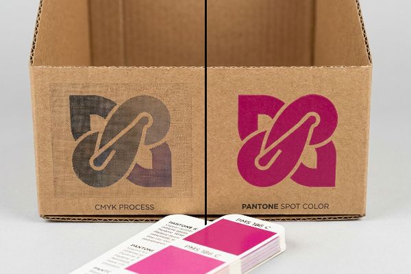 Corrugated boxes contrasting CMYK Process halftone grain with vibrant Pantone Spot Color PMS 186 C, showing superior pigment.