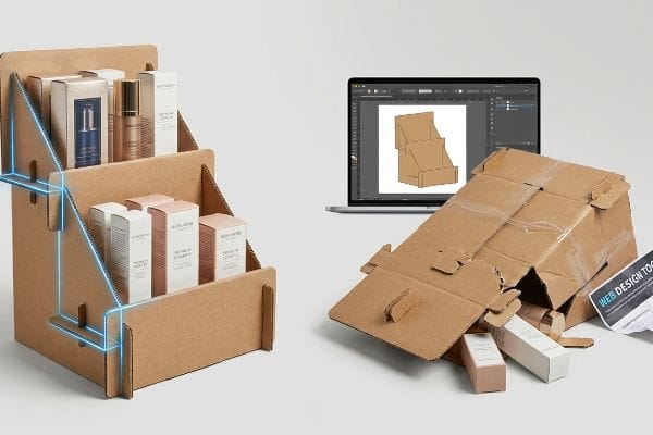 Corrugated cardboard display with Natalie Cosmetics products, beside a laptop showing a structural template and a collapsed homemade display.