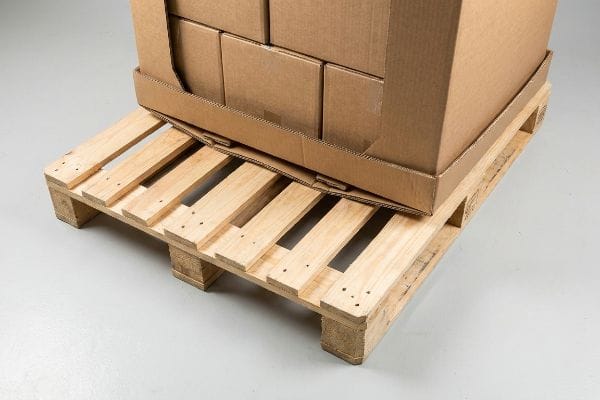 Corrugated cardboard box base sagging into wide wooden export pallet deck gaps, illustrating the pallet loading problem.