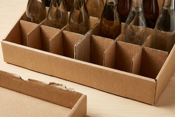 Brown corrugated cardboard tray with modular dividers, precisely separating amber glass bottles for retail product display.