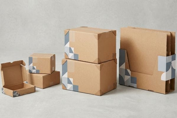Kraft corrugated shipping boxes with blue and grey geometric corner designs, suitable for e-commerce and B2B packaging.
