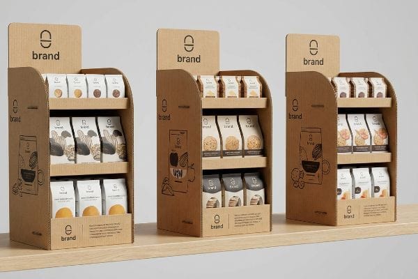 Three corrugated cardboard POP displays from 'Brand' feature various packaged snacks, with minimalist line art illustrations on the side panels.