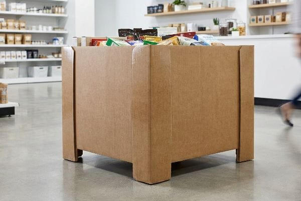 In a retail store, a durable double-wall corrugated cardboard display bin holds various packaged products, designed for high-traffic aisles.