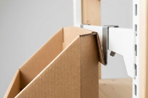 A steel S-clip securely anchors a corrugated paperboard retail hanging display rack to a white metal shelving fixture.