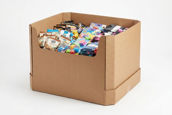 A retail cardboard dump bin, made from corrugated material, filled with impulse purchase items including Lay's chips, Planters peanuts, small toys, and folded socks.