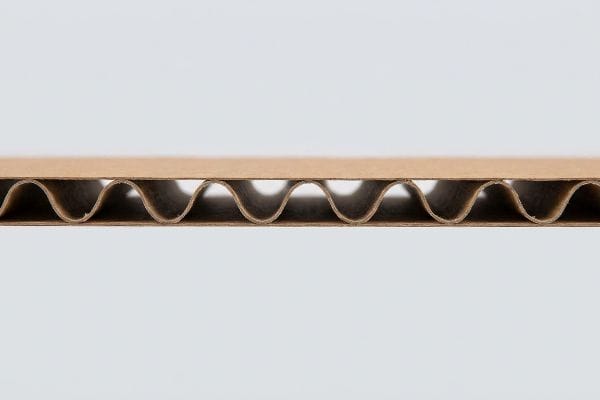 Brown kraft corrugated paperboard cross-section revealing wavy internal flutes.