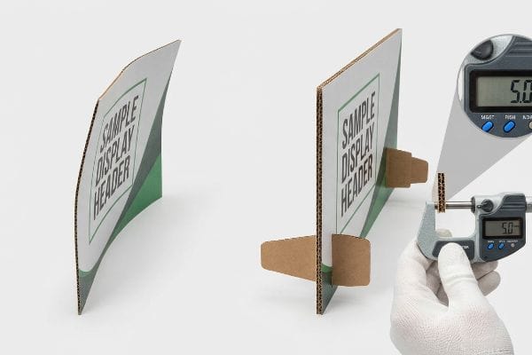 A warped corrugated Sample Display Header contrasted with a flat 5.0mm thick header measured by a micrometer.