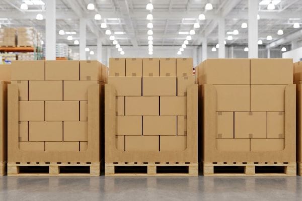 Three corrugated pallet displays with brown boxes on wooden pallets, ready for high-volume retail logistics in a warehouse.