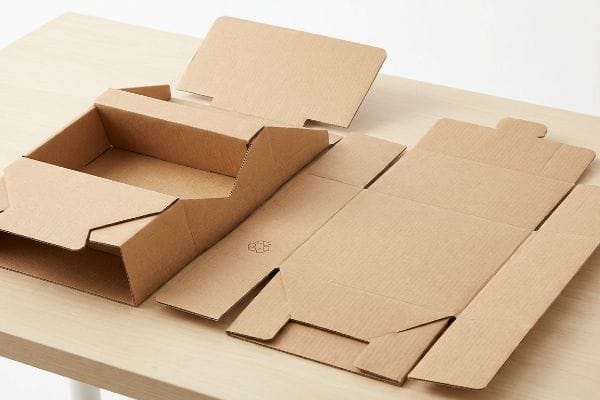 Partially assembled eco-friendly corrugated testliner POP display next to a flat-packed sustainable cardboard piece.