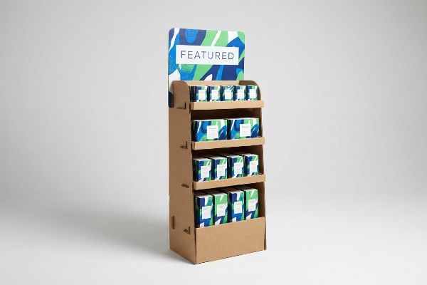 A freestanding retail point-of-purchase display made of corrugated cardboard, featuring four shelves of blue and green patterned product boxes and a 'Featured' header.