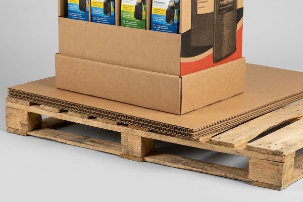 Corrugated slip sheets on a wooden pallet, supporting a cardboard display box to prevent bottom-tier sag and distribute load.