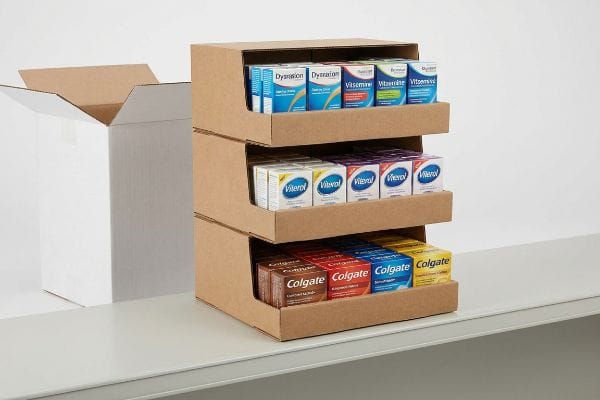 Corrugated three-tier PDQ shelf display filled with Dysration, Vitamine, Viterol, and Colgate products, next to an open shipping carton, ready for retail deployment.