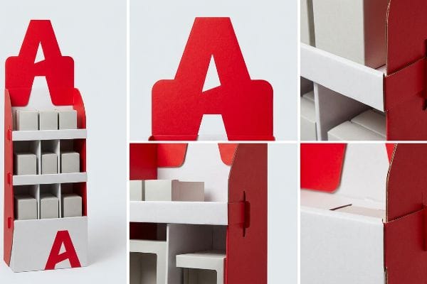 Red and white paperboard point-of-purchase display with a large die-cut 'A' header, modular shelves holding small boxes, and a lower 'A' graphic.