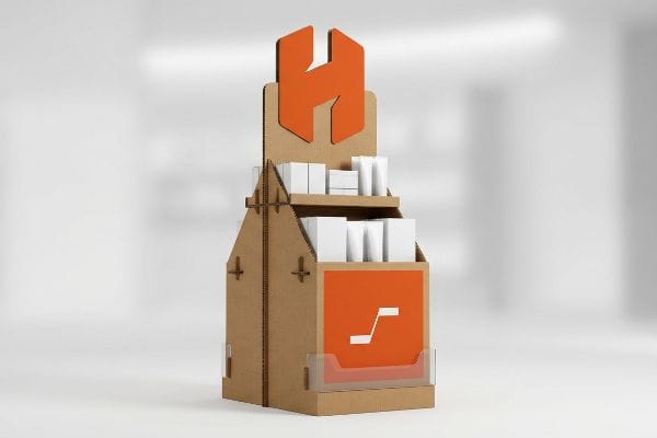 Corrugated cardboard end cap display with an orange die-cut H logo, two shelves holding white product boxes, and a front orange graphic panel.
