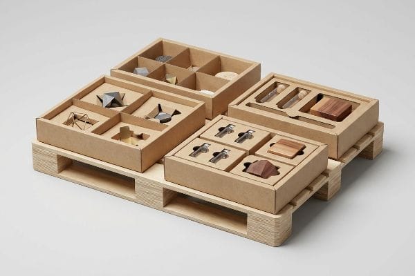 Modular cardboard display boxes with custom die-cut trays hold diverse small items on a fractional wooden pallet.