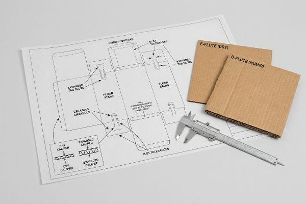 Dieline showing Creasing Channels, Expanded Tab Slots, and Slot Tolerances, with E-Flute (Dry), B-Flute (Humid) cardboard, and a caliper.