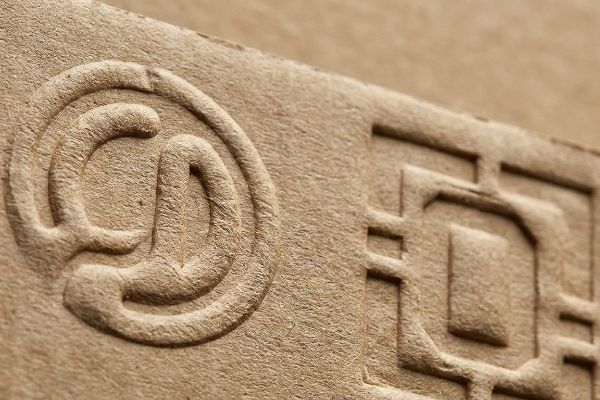 Embossed circular and geometric patterns create tactile texture on brown corrugated paper, highlighting 3D design for packaging.