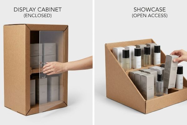 Brown corrugated display cabinet, a hand opening its clear door to reveal stacked product boxes, labeled Display Cabinet (Enclosed).
