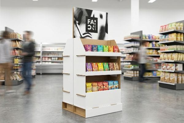 White corrugated FSDU with Fa:on Nitro header, displaying colorful packaged snacks on three shelves in a busy supermarket aisle.