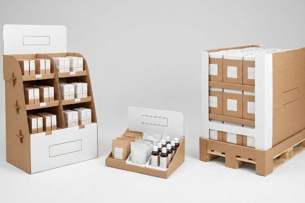 Corrugated cardboard retail displays: freestanding floor merchandiser, countertop unit, and pallet structure, filled with products.