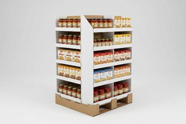 Fractional Pallet Display White cardboard fractional pallet merchandiser, fully stocked with jars of pasta sauce and pasta boxes, rests on a brown corrugated base.