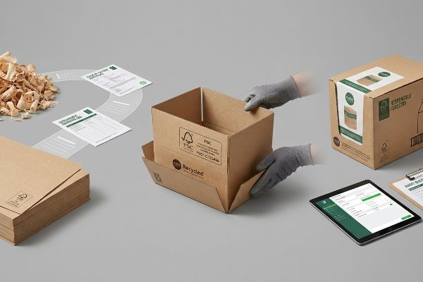 Brown FSC Recycled cardboard box assembly by gloved hands, with Responsible Sourcing Ltd. documents, wood shavings, and a tablet for responsible forestry.