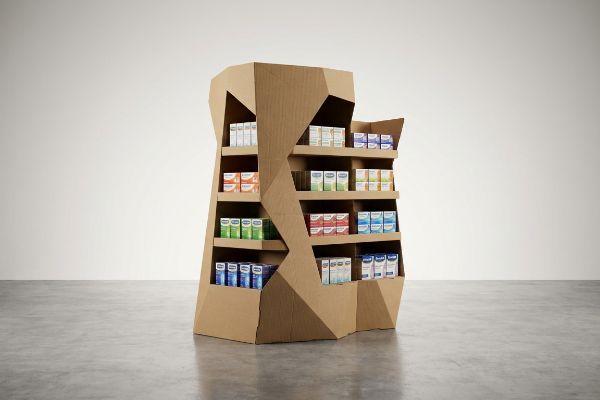 A geometrically shaped corrugated cardboard floor display unit showcasing various small product boxes on multiple shelves, designed for retail merchandising.