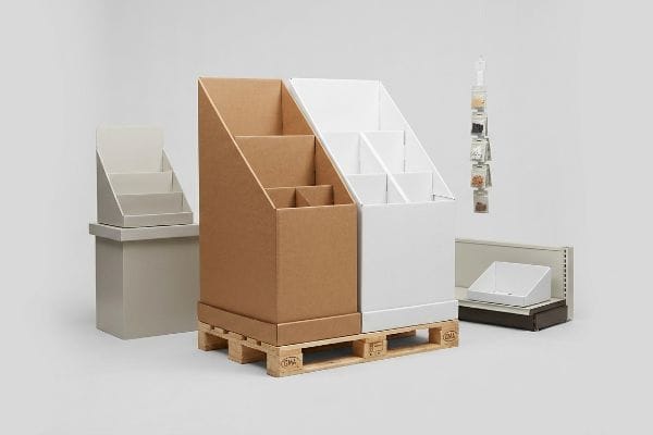 Brown and white corrugated cardboard floor merchandisers on a Gma Epal wooden pallet, alongside a grey countertop unit and a hanging clip strip.
