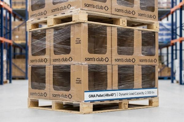 Pallets stacked with Sam's Club display boxes, shrink-wrapped for transit, featuring 'shop-through visibility' and a label detailing 'GMA Pallet (48x40")' and 'Dynamic Load Capacity: 2,500 lbs'.