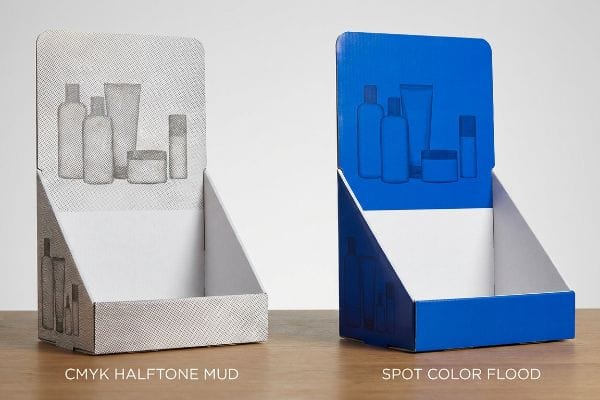 Two cardboard display stands demonstrate print quality: a grainy CMYK Halftone Mud next to a vibrant Spot Color Flood for cosmetic products.