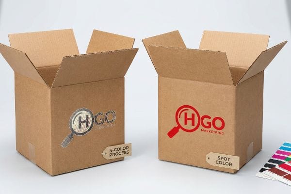 CMYK vs Spot Color Two open corrugated cardboard boxes showcasing HGO Marketing logos: one muddy 4-Color Process, one vibrant red Spot Color.