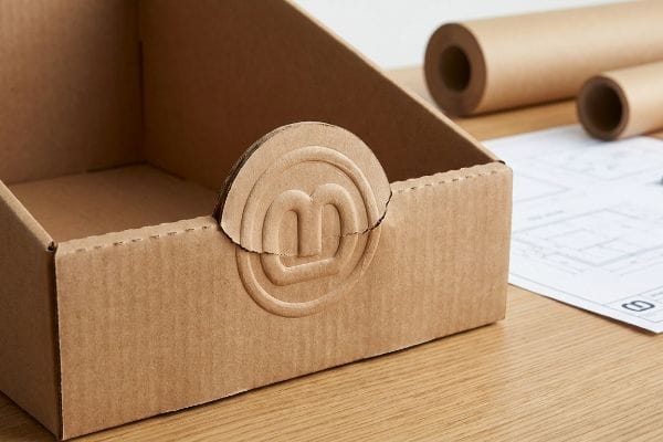 Kraft corrugated PDQ tray with an inward debossed 'B' logo, demonstrating structural integrity.