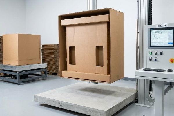 Brown corrugated box suspended above a concrete slab during an Ista 3A drop test, validating packaging transit survivability.