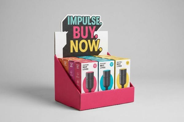 A vibrant magenta Counter Display Unit features a die-cut header with 'Impulse. Buy. Now.' above colorful 'Pantone Brot Lover' product boxes.