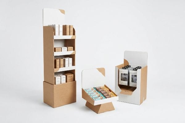 Aufsteller aus Kraftkarton, darunter ein hohes Bodendisplay, ein offenes Thekendisplay für Snackbars und ein kleineres POS-Display, zur Präsentation von Lösungen für den Einzelhandel.